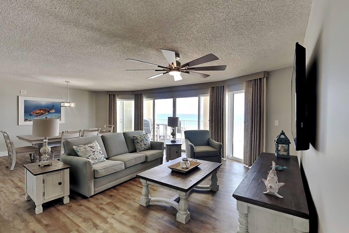 A living room with a ceiling fan, a sofa, a coffee table, and a TV on a stand.