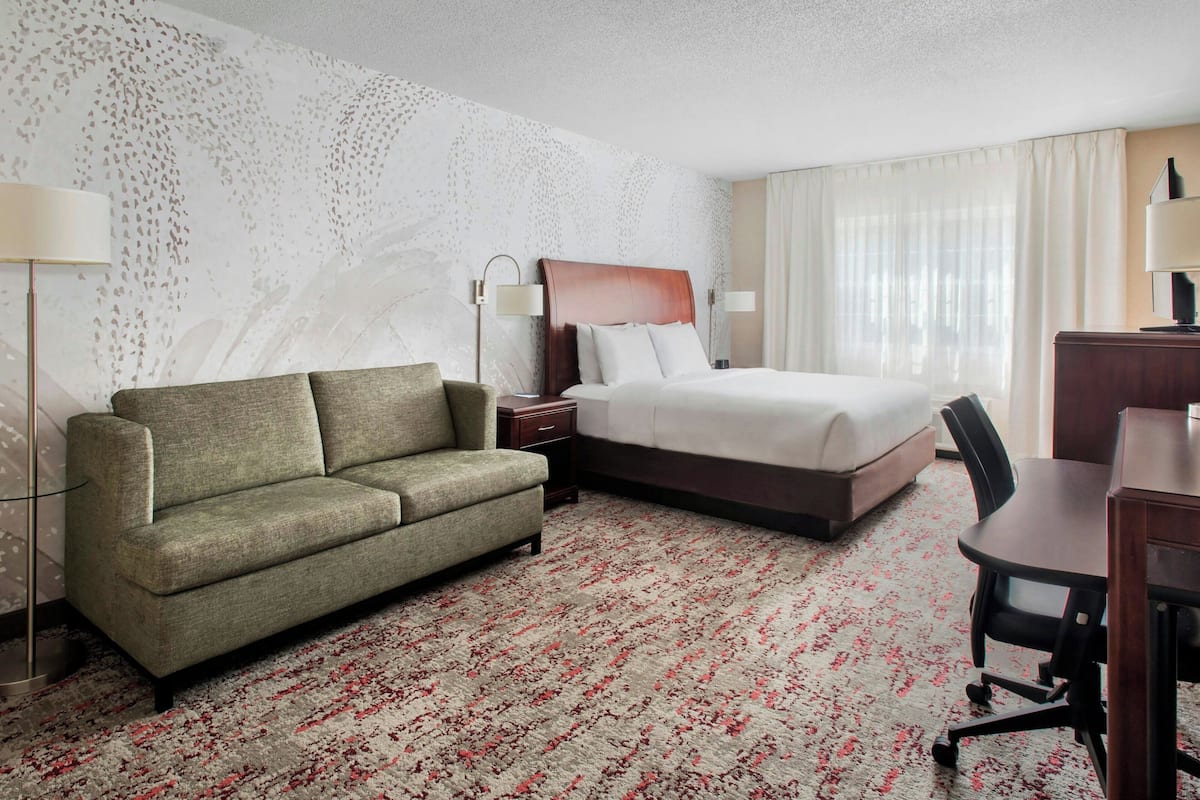 Una habitación de hotel con cama, sofá, escritorio y una silla.