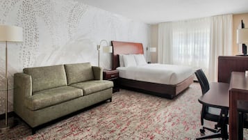 Una habitación de hotel con cama, sofá, escritorio y una silla.