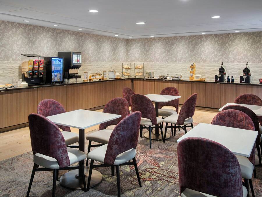 Una habitación de hotel con barra de desayuno, zona de estar y minibar.