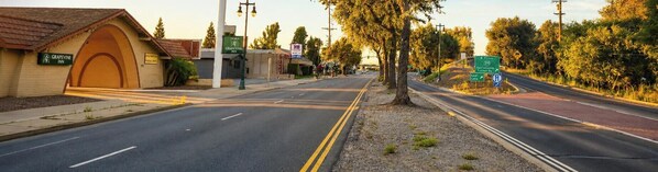A Grapevine Inn with a large arched entrance, a street view with a road leading to a roundabout, and directional signs for local destinations. - Grapevine Inn (Lodi)