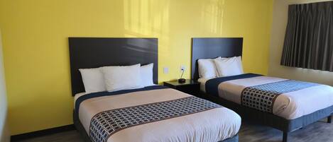 A hotel room with two beds, each with a dark headboard and white bedding.