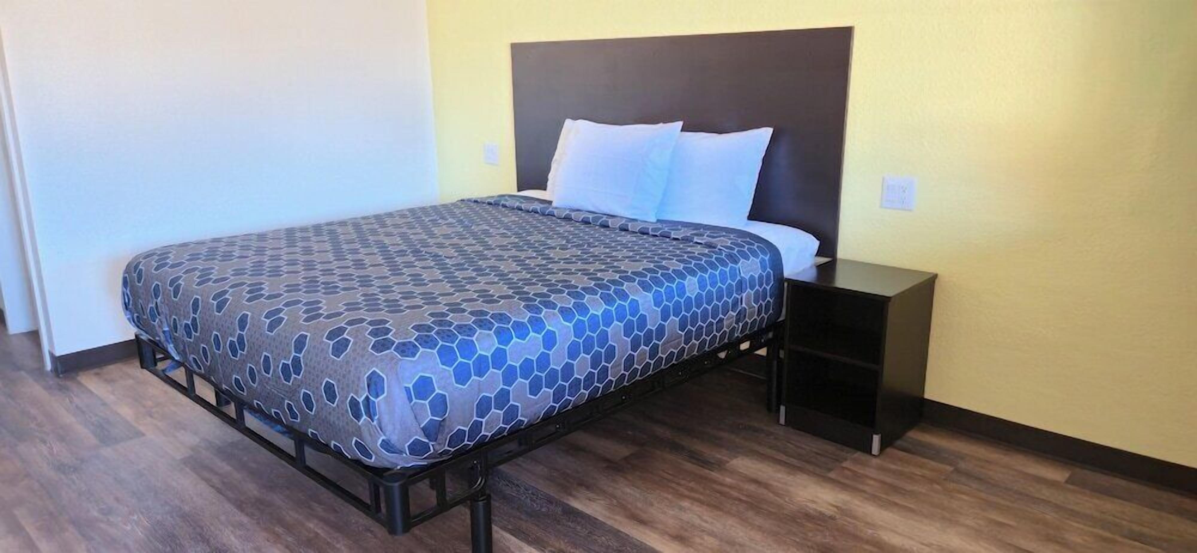Un letto con una coperta a motivi, un comodino e una testiera.