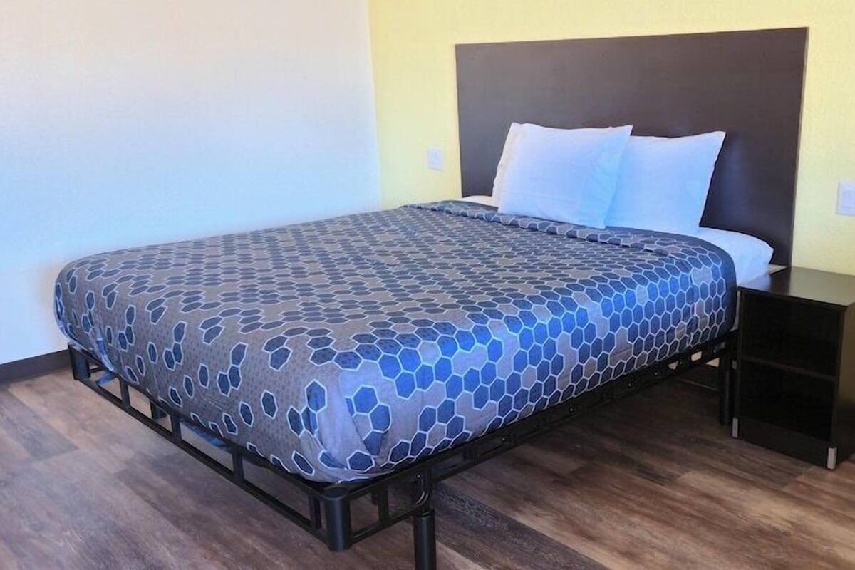 A bed with a patterned bedspread, a nightstand, and a headboard.