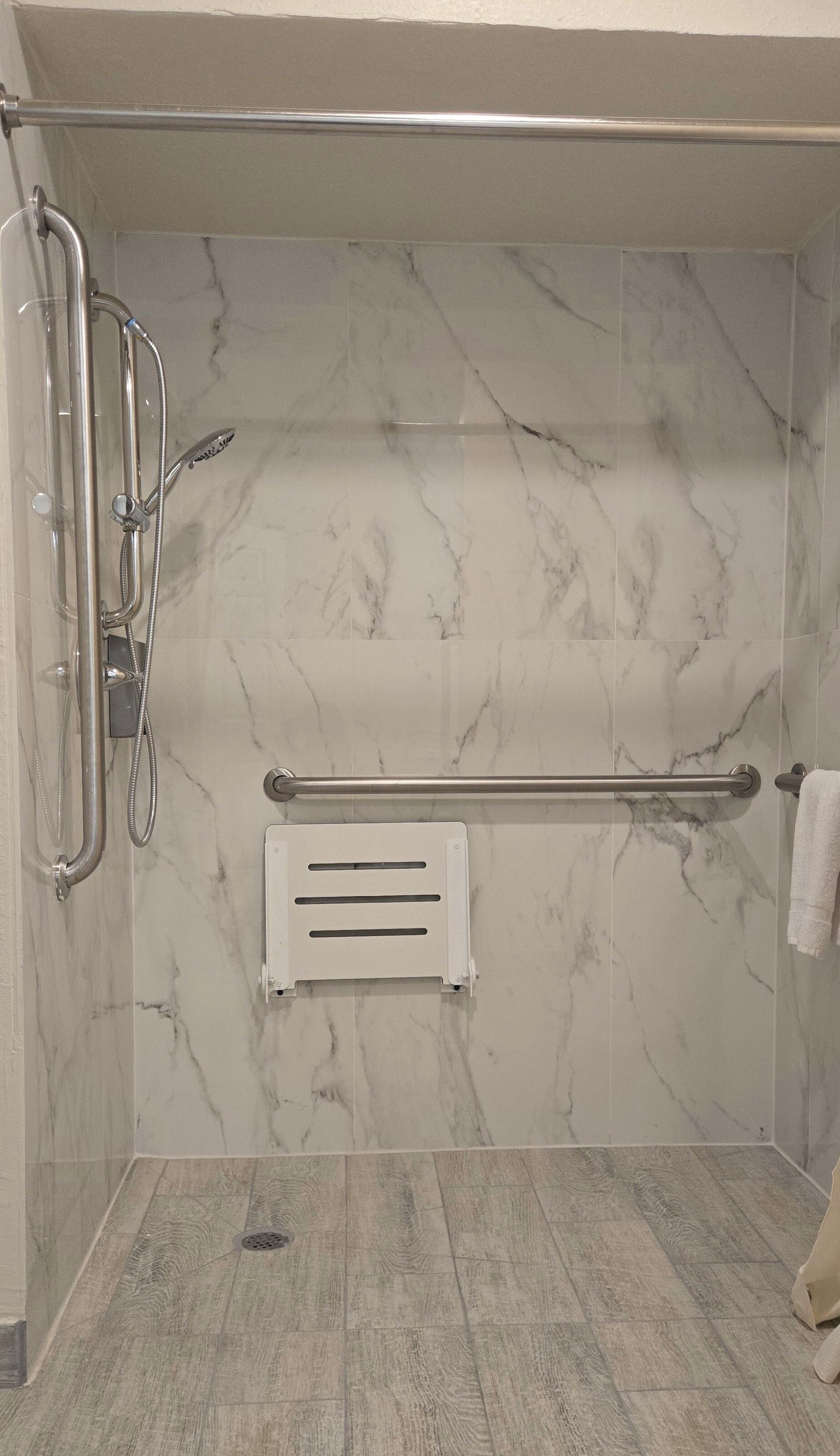 A bathroom with a shower, a towel rack, and a hand dryer.