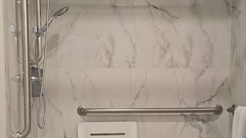 A bathroom with a shower, a towel rack, and a hand dryer.