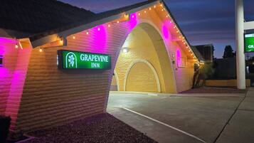 A brick building with a sign for Grapevine Inn, featuring an arched entrance and string lights.
