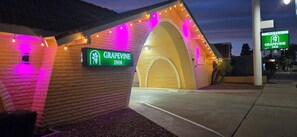 Um edifício de tijolos com a placa do Grapevine Inn, apresentando uma entrada em arco e luzes de corda.
