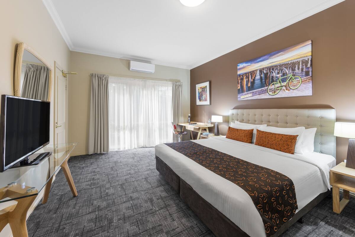 Une chambre d’hôtel avec un grand lit, une télévision, un bureau et une chaise.