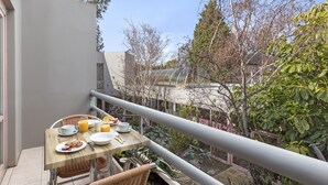 Uma varanda com mesa posta para o café da manhã, incluindo pratos, copos e suco de laranja.