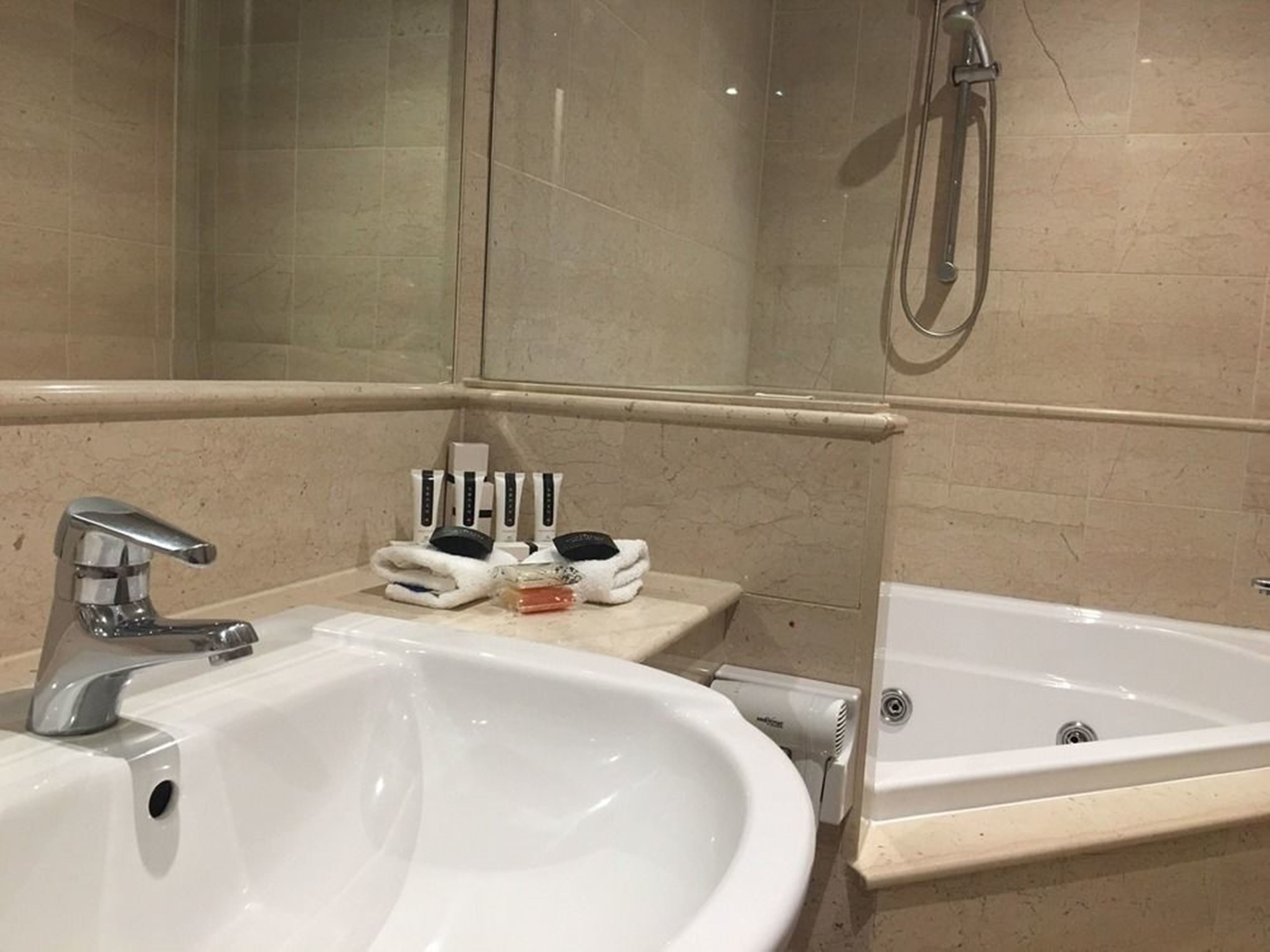 Un baño con un lavamanos grande, una bañera y una ducha. Hay artículos de aseo en la encimera.