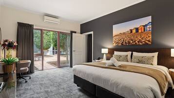 Habitación de hotel con cama, escritorio con lámpara, silla y vista al exterior a través de un ventanal.