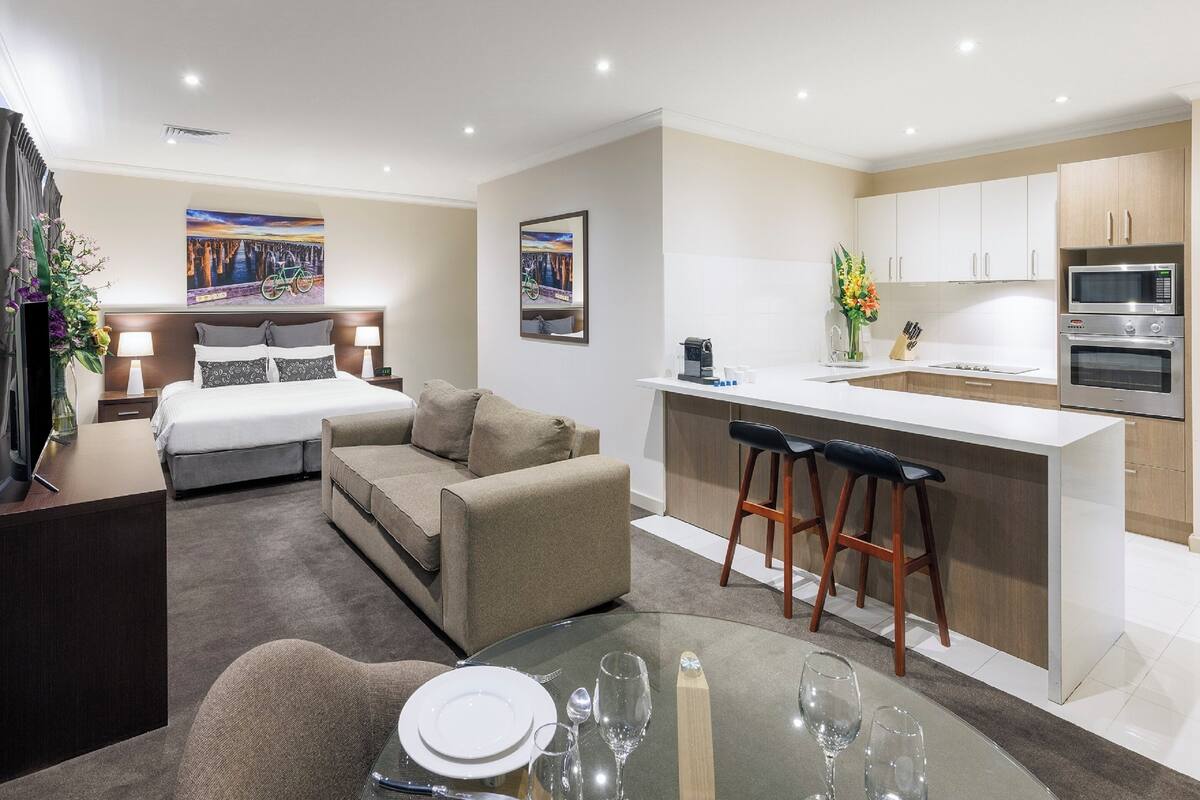 Une chambre d’hôtel moderne équipée d’un lit, d’un canapé, d’une table à manger et d’une kitchenette.