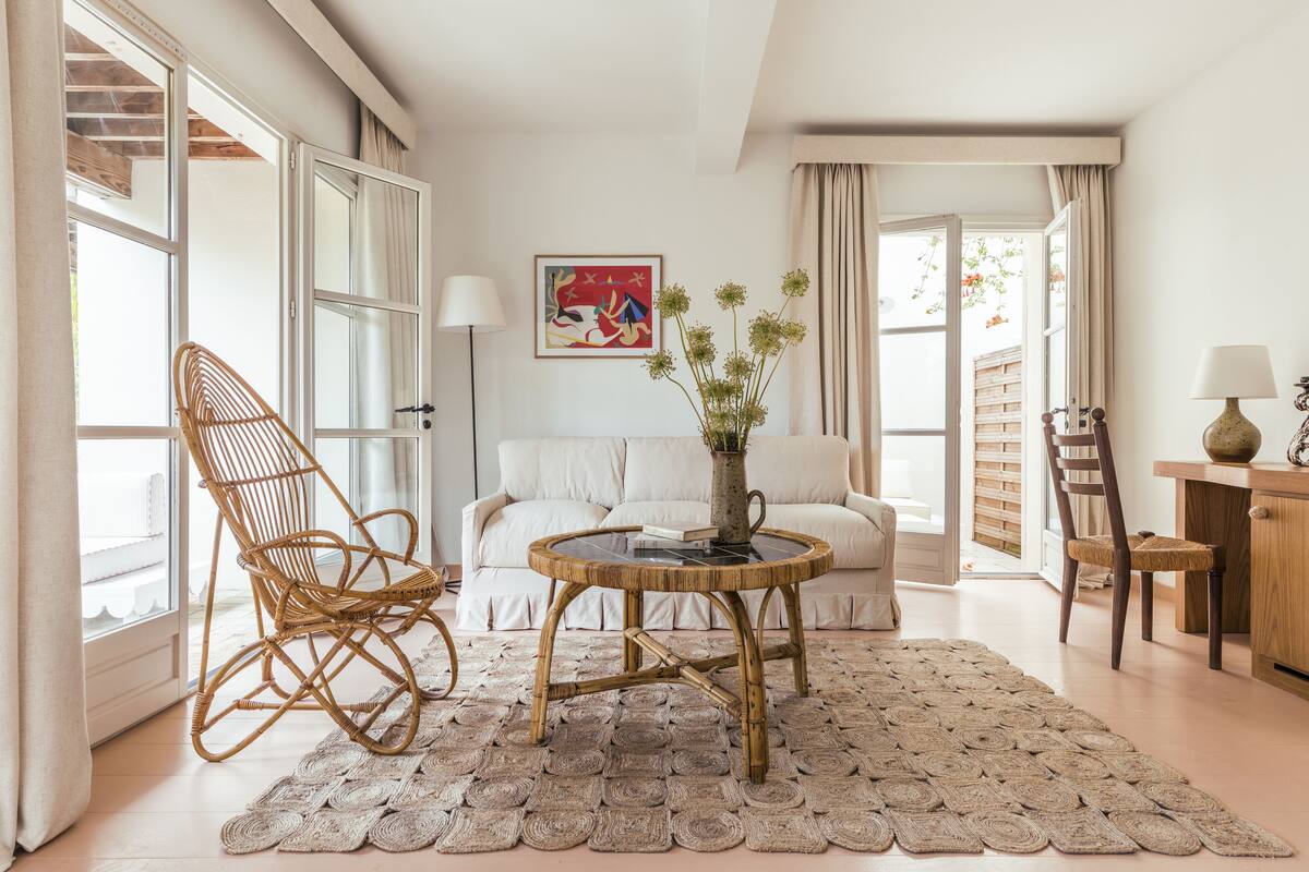 Een gezellige woonkamer met een rieten stoel, een ronde salontafel en een bank.