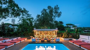 A poolside area with lounge chairs, a bar, and a pool.