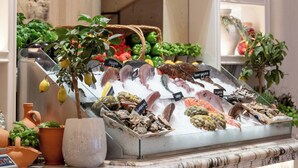 A kitchen counter with a variety of fresh produce, decorative jars, and potted plants.