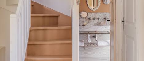 A staircase leading to a bathroom with a marble sink and a mirror.