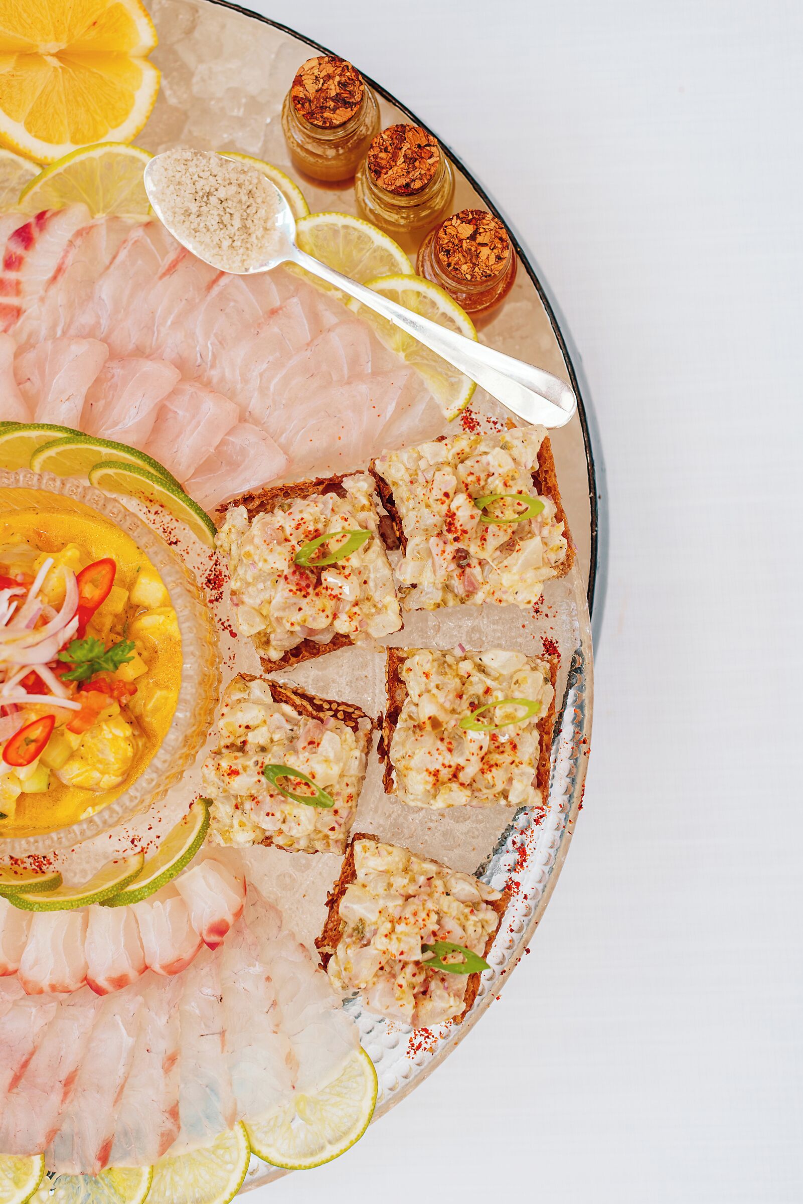 A seafood platter with various types of fish and a bowl of soup.