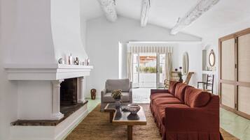 A living room with a fireplace, a sofa, a coffee table, and a view of the outdoors.
