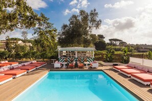 A poolside area with lounge chairs, a bar, and a view of the surrounding landscape. - Hôtel La Tartane Saint -Tropez (Saint-Tropez)