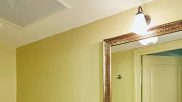 A bathroom with a white sink, a mirror with a decorative frame, and a toilet.