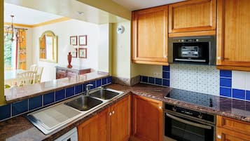 A kitchen with wooden cabinets, a built-in microwave, a stainless steel sink, and a dishwasher.