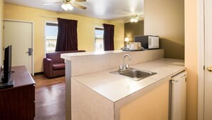 A compact kitchen with a sink, a ceiling fan, and a refrigerator.