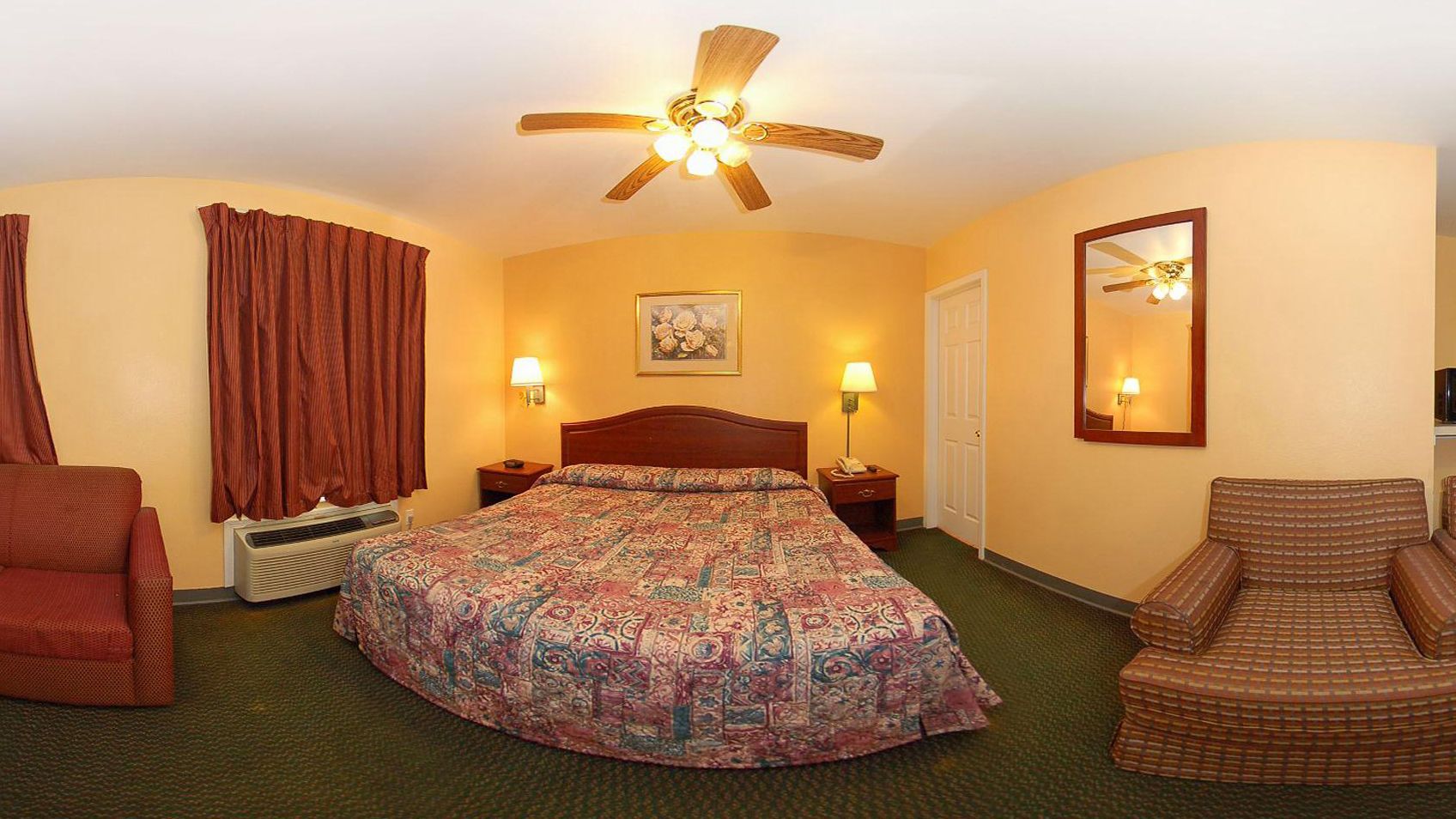 Une chambre d’hôtel avec un lit, une chaise, un ventilateur de plafond et un radiateur.