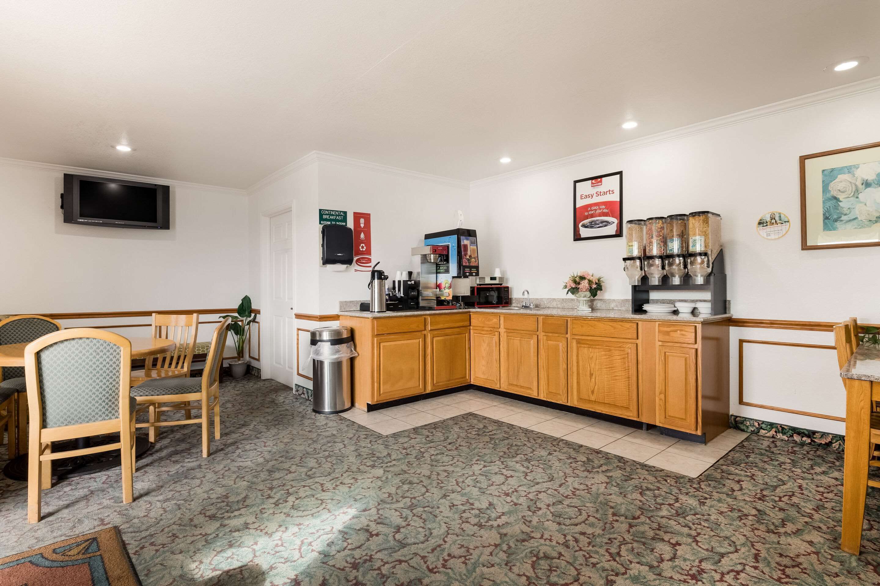 A kitchen with wooden cabinets, a coffee machine, and a trash bin.