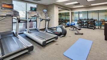 Un gimnasio con cintas de correr, bicicletas estáticas y pelotas de ejercicio.