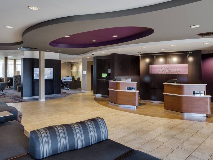 Un moderno vestíbulo de hotel con mostrador de recepción, zona de estar y ventanas amplias.