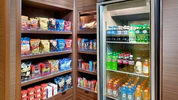 A snack and beverage refrigerator stocked with various brands of chips, snacks, and drinks.
