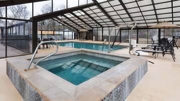 Piscina ao ar livre coberta, com borda em azulejo, prancha de salto e cadeiras de sol sob um telhado metálico.