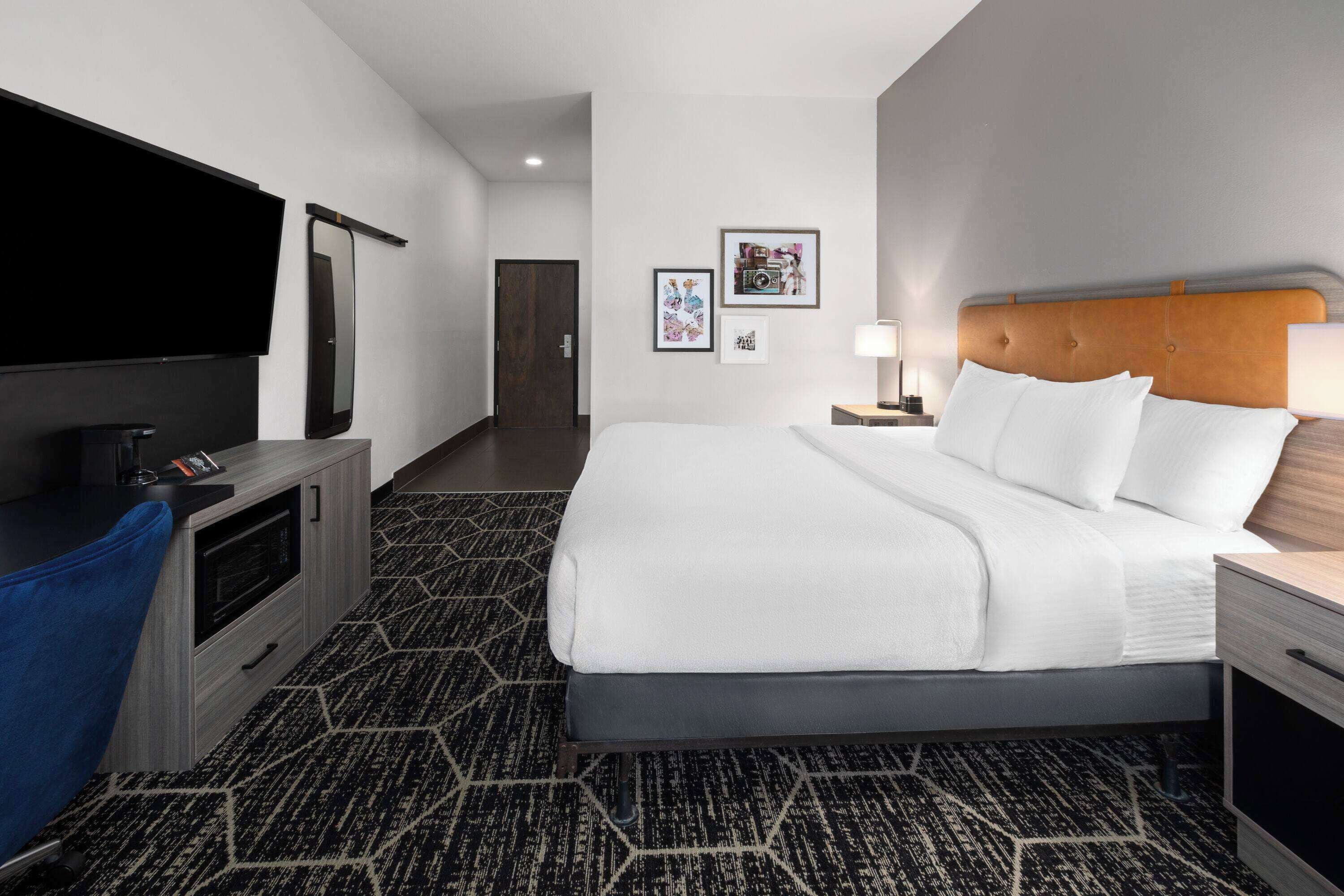 A hotel room with a bed, a TV, a desk, and a mirror.