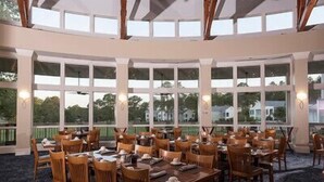 A restaurant with multiple tables and chairs, large windows, and a view of the outside. - Lake Blackshear Resort & Golf Club (Cordele)