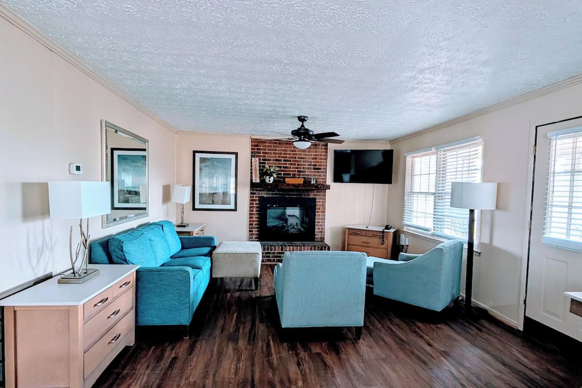 Ein Wohnzimmer mit Kamin, Deckenventilator und Wandfernseher.