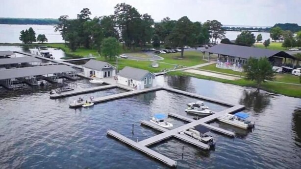 A marina with docks and boats, surrounded by greenery and a lake. - Lake Blackshear Resort & Golf Club (Cordele)