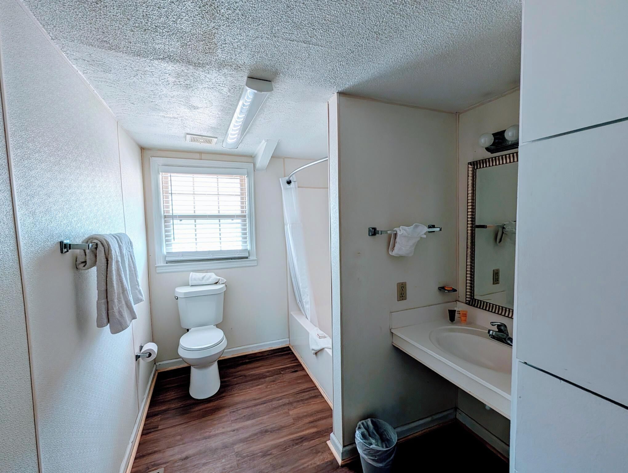 Une salle de bain équipée de toilettes, d’une douche, d’un lavabo et d’un miroir.