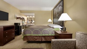 Habitación de hotel con cama, televisión, escritorio, silla y lámpara.