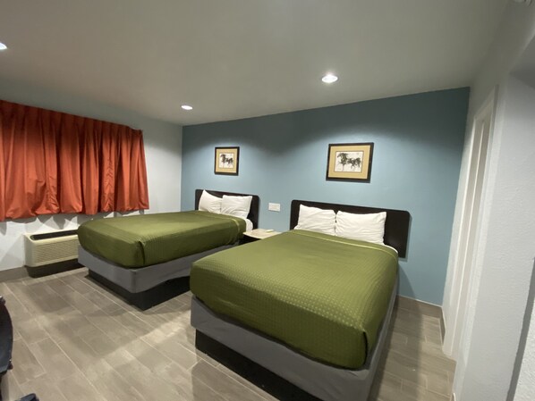 Habitación de hotel con dos camas, una cortina roja y dos cuadros en la pared.