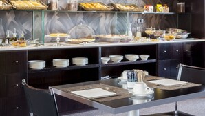 Un buffet proposant une variété de plats et de boissons, une table à manger dressée et un mur à motifs en arrière-plan.