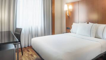 Habitació d'hotel amb un llit, una taula de nit i una làmpada.