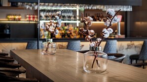 A bar area with wooden tables and chairs, clear glass vases with dried flowers, and a well-lit background with shelves of bottles. - AC Hotel Ponferrada by Marriott (Ponferrada)