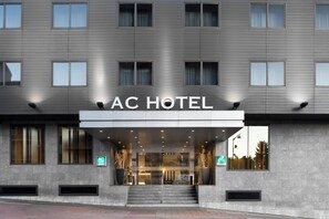 Exterior del Hotel AC, con fachada moderna, amplias ventanas y una entrada destacada.