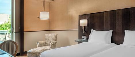 Habitación de hotel con una cama grande, una silla, una mesa y vistas al exterior.