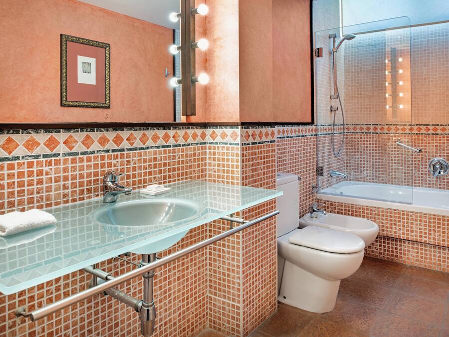 A bathroom with a glass sink, a toilet, and a bathtub.