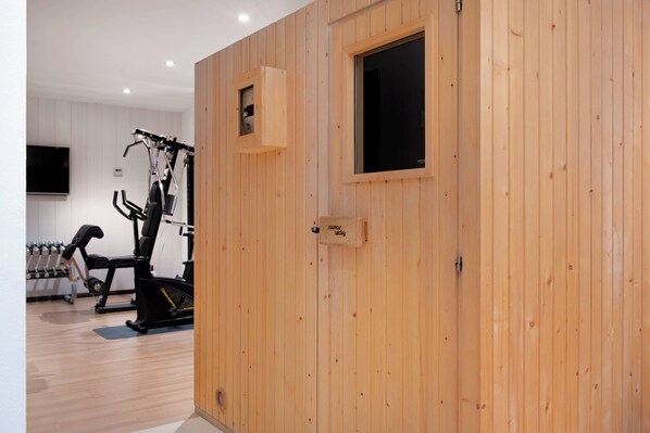 Un gimnasio con equipo de ejercicio, paredes de madera y un televisor.