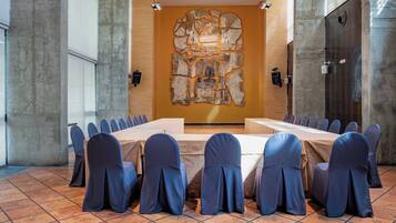 A conference room with a long table, blue chairs, and a stone wall decoration.