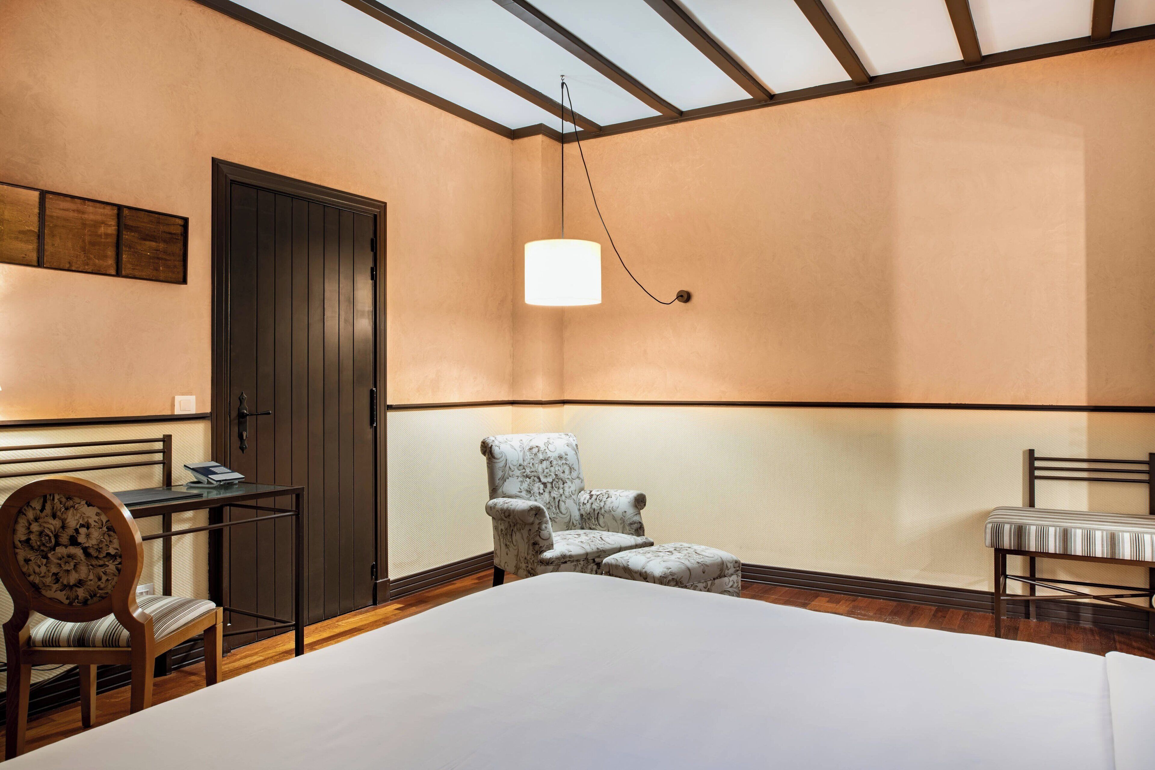Una habitación de hotel con cama, escritorio, silla y banco.