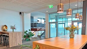 A modern interior with a wooden reception desk, potted plants, and hanging pendant lights. - Griffen Spahotel (Ronne)